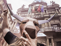 Activist against animal cruelty in bull fightings  wears a paperboard bullhead mask under the Pamplona city council building, Spain before t...