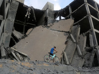 Palestinians walk through the wreckage of a building that was damaged by Israeli air strikes in Gaza City on July 15, 2018. Israel's militar...