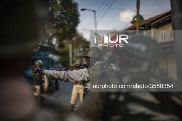 An Indian paramilitary trooper shoots  stones with his catapult at Kashmiri Muslim protesters during a protest against the killing of a Kash...