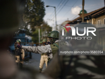 An Indian paramilitary trooper shoots  stones with his catapult at Kashmiri Muslim protesters during a protest against the killing of a Kash...