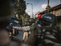 An Indian paramilitary trooper shoots  stones with his catapult at Kashmiri Muslim protesters during a protest against the killing of a Kash...