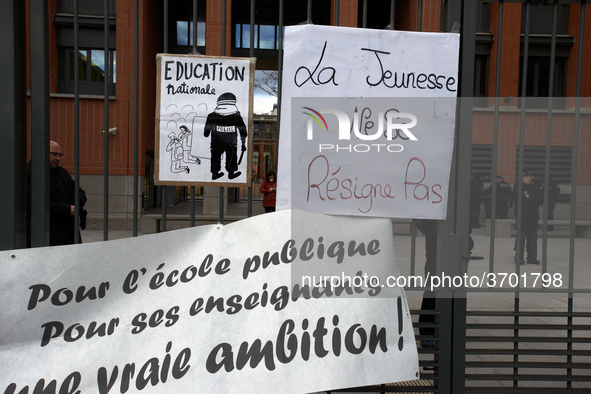 A placard on the metal gate of the Local Board of Education of Toulouse reads 'Youths don't resign themselves' and a banner reads 'For a pub...