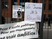 A placard on the metal gate of the Local Board of Education of Toulouse reads 'Youths don't resign themselves' and a banner reads 'For a pub...