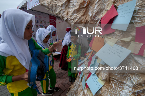 Students write their hopes on paper and then put them on an artificial tree in the Back to School Campaign held by Sayangi Tunas Cilik Found...