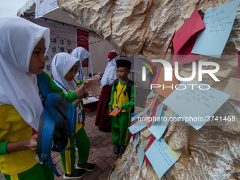 Students write their hopes on paper and then put them on an artificial tree in the Back to School Campaign held by Sayangi Tunas Cilik Found...