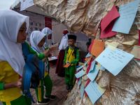 Students write their hopes on paper and then put them on an artificial tree in the Back to School Campaign held by Sayangi Tunas Cilik Found...