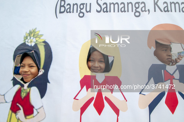 Students take pictures on a vehicle playing in the Back to School Campaign held by the Sayangi Tunas Cilik Foundation (STC) at Vatulemo Fiel...