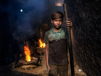 Shihab (8) works in a metal shop near shipyard where he breaks metal small pieces and puts them into the furnace. Dhaka, Bangladesh, Februar...