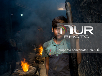 Shihab (8) works in a metal shop near shipyard where he breaks metal small pieces and puts them into the furnace. Dhaka, Bangladesh, Februar...