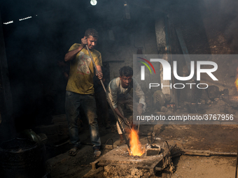 Workers work in a metal shop near shipyard where he breaks metal small pieces and puts them into the furnace. Dhaka, Bangladesh, February 7,...