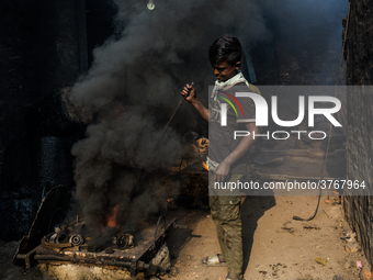 A child worker works in a metal shop near shipyard where he breaks metal small pieces and puts them into the furnace. Dhaka, Bangladesh, Feb...