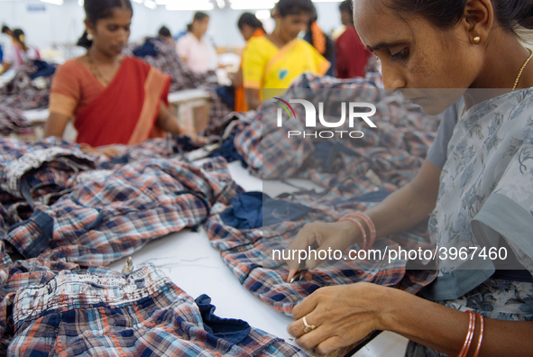 A seamstress removing threads from clothing destined for the US market at a garment factory in Bangalore. Many of the workers emigrate from...