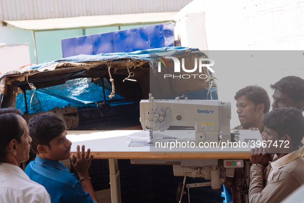 Workers moving a sewing machine at a garment factory in Bangalore. Many of the workers emigrate from poor regions of the country, making clo...