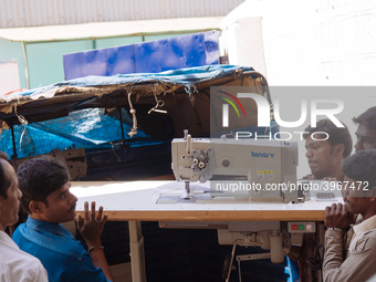 Workers moving a sewing machine at a garment factory in Bangalore. Many of the workers emigrate from poor regions of the country, making clo...