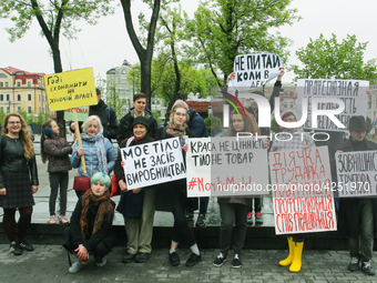 A few young people mark May Day standing with a placards which say "Enough to save on women's labor", "Trade union activity is not a crime",...