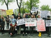 A few young people mark May Day standing with a placards which say "Enough to save on women's labor", "Trade union activity is not a crime",...