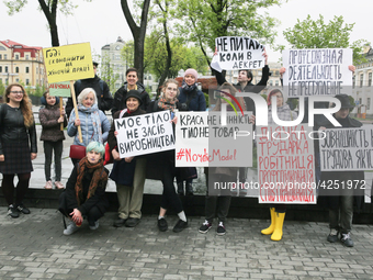 A few young people mark May Day standing with a placards which say "Enough to save on women's labor", "Trade union activity is not a crime",...