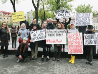 A few young people mark May Day standing with a placards which say "Enough to save on women's labor", "Trade union activity is not a crime",...