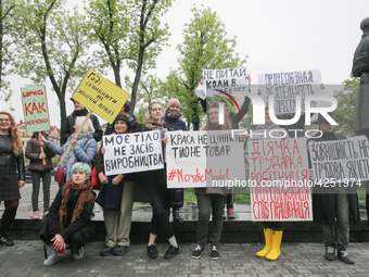 A few young people mark May Day standing with a placards which say "Enough to save on women's labor", "Trade union activity is not a crime",...