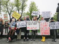 A few young people mark May Day standing with a placards which say "Enough to save on women's labor", "Trade union activity is not a crime",...