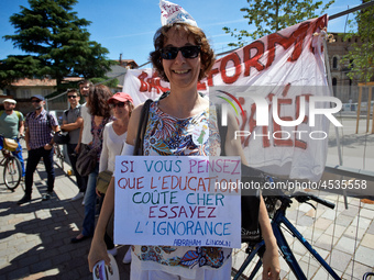 A teacher holds a placrad reading 'If you are thinking that education costs too much, try ignirance !'. Some high school teachers were on st...