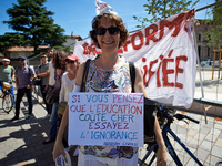 A teacher holds a placrad reading 'If you are thinking that education costs too much, try ignirance !'. Some high school teachers were on st...