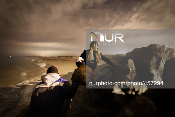 After climbing through a wall of rocks separating the beach from the port, a group of migrants attempt smuggling themselves into the port's...