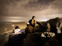 After climbing through a wall of rocks separating the beach from the port, a group of migrants attempt smuggling themselves into the port's...