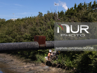 A man washes himself coming out of a pipe close to a factory. This water should end in the river behind him. It is hard to tell if the use o...