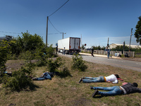 While some migrants rest after a sleepless night, others  run after a passing by truck to try to jump inside the cargo compartment. These at...