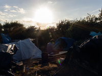 A man prays in a base camp in an area known as "the jungle" which is closer to the port than the official migrant camp in Calais and offers...