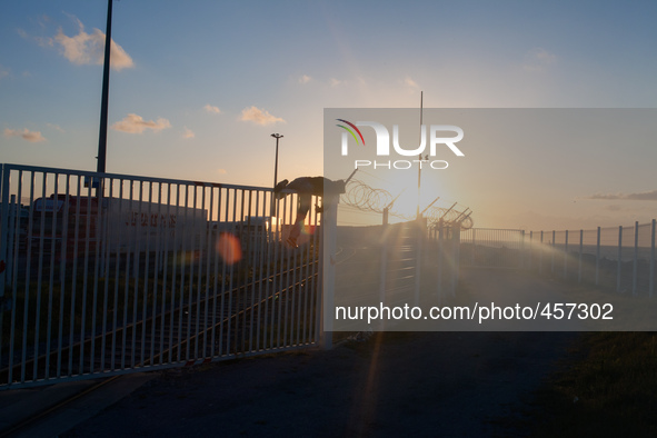 A migrant is seen climbing over a barrier to access the truck parking lot as the sun sets. Calais, France, June 2014.

For the last 20 yea...