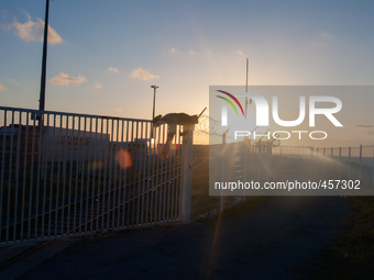 A migrant is seen climbing over a barrier to access the truck parking lot as the sun sets. Calais, France, June 2014.

For the last 20 yea...