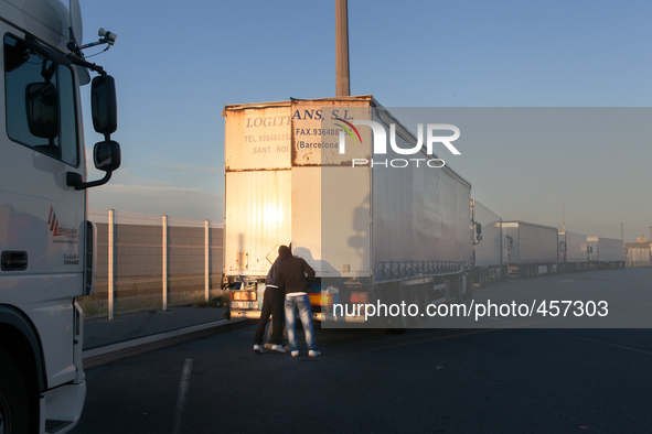 A couple of migrants examine the interior of a truck inside port's the parking lot. The best way to find out if vehicle is heading towards t...