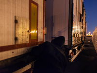 A migrant sticks his head out on the look out for guardians inside the port's truck parking lot. Calais, France, June 2014.

For the last...