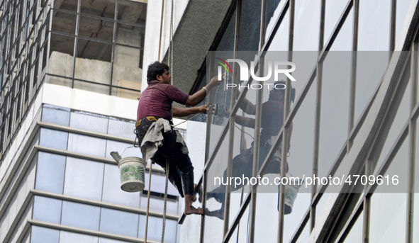 A worker cleans glass window of a building in Kolkata, India, 24 July, 2019  