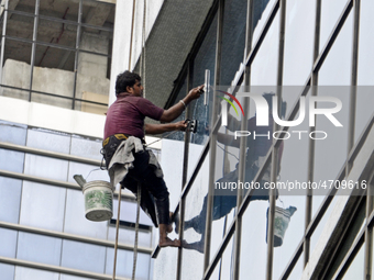 A worker cleans glass window of a building in Kolkata, India, 24 July, 2019  (