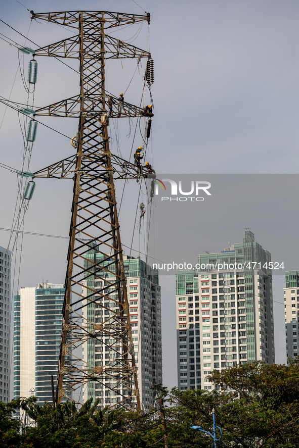 Operators work on a high voltage tower in Jakarta, Indonesia, July 27, 2019.  