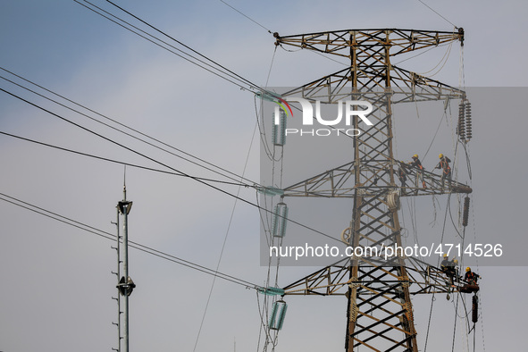 Operators work on a high voltage tower in Jakarta, Indonesia, July 27, 2019.  