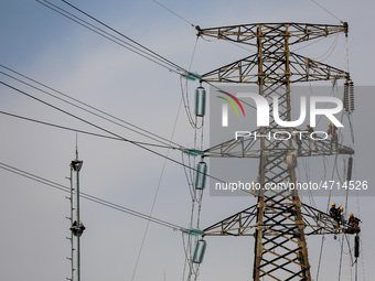 Operators work on a high voltage tower in Jakarta, Indonesia, July 27, 2019.  (