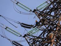 Operators work on a high voltage tower in Jakarta, Indonesia, July 27, 2019.  (