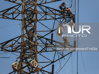 Operators work on a high voltage tower in Jakarta, Indonesia, July 27, 2019.  (