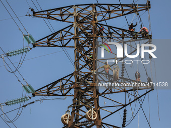 Operators work on a high voltage tower in Jakarta, Indonesia, July 27, 2019.  (