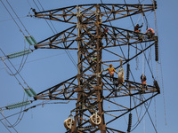 Operators work on a high voltage tower in Jakarta, Indonesia, July 27, 2019.  (