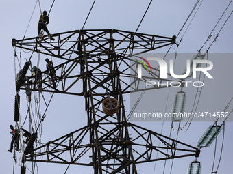 Operators work on a high voltage tower in Jakarta, Indonesia, July 27, 2019.  (