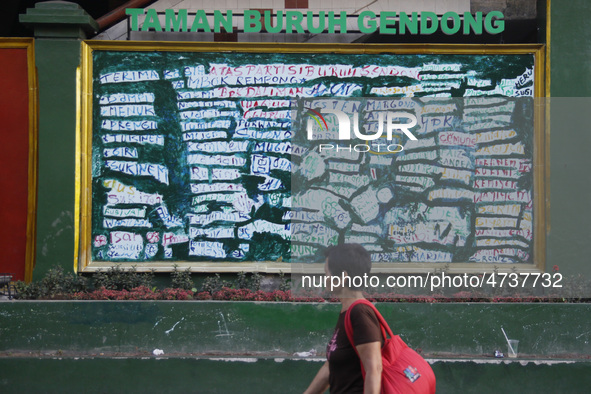 A women passing through the Taman Buruh Gendong (Freight Workers park) which the names of the workers written on the wall as a form of appre...