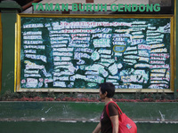 A women passing through the Taman Buruh Gendong (Freight Workers park) which the names of the workers written on the wall as a form of appre...