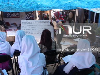 Cijeruk 1 Junior High School students openly study in the yard of a resident's house with a tarpaulin roof in Palasari Village, Bogor Regenc...