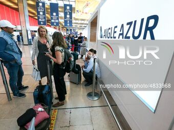 Passengers wait in front of the French airline Aigle Azur’s reception desk, without any employees, at Orly airport, France  on September 6,...