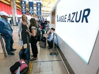 Passengers wait in front of the French airline Aigle Azur’s reception desk, without any employees, at Orly airport, France  on September 6,...